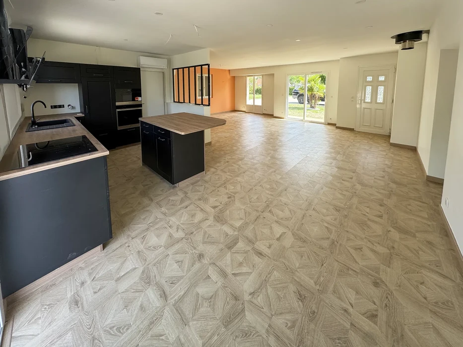 Intérieur moderne d'une maison rénovée avec cuisine ouverte équipée de meubles noirs et plan de travail en bois