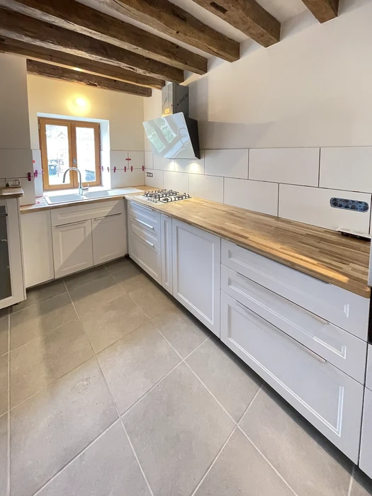 Cuisine moderne rénovée dans une maison ancienne avec poutres apparentes en bois