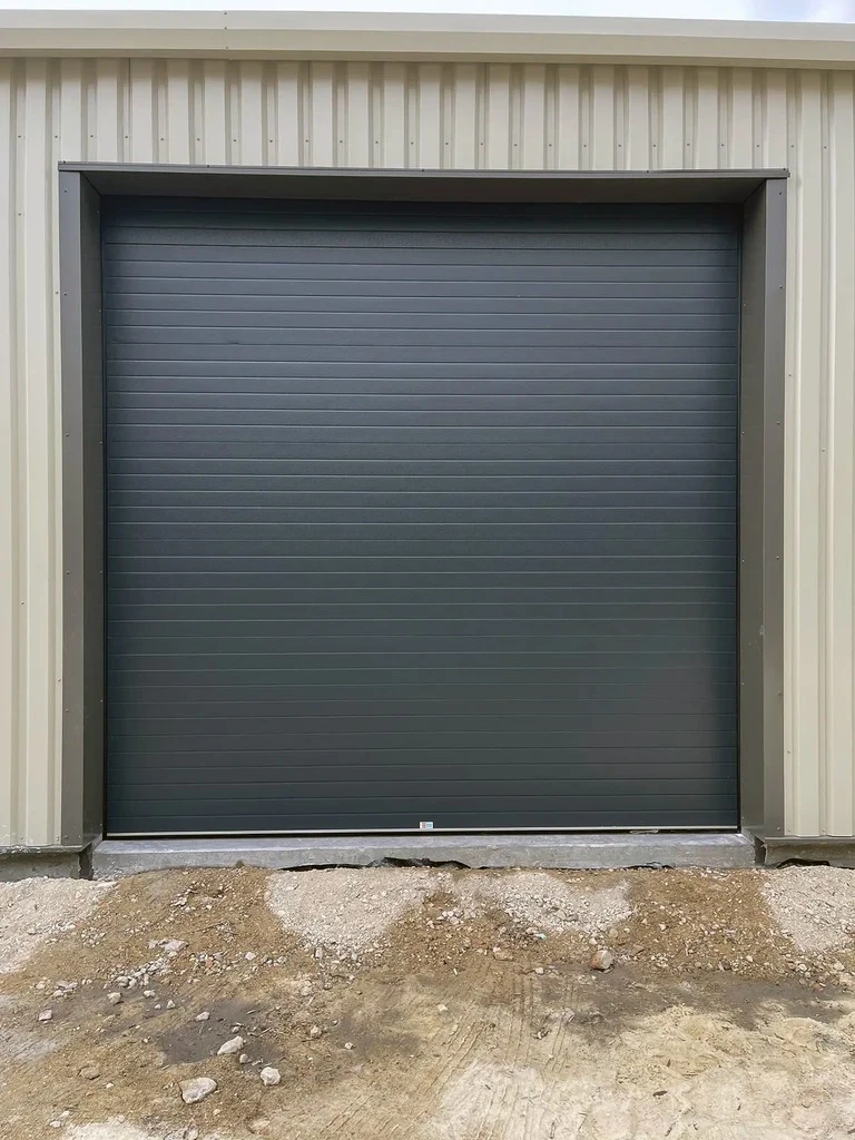 Extérieur résidentiel avec portail automatique coulissant rouge vif en métal laqué, installé entre piliers de briques multicolores