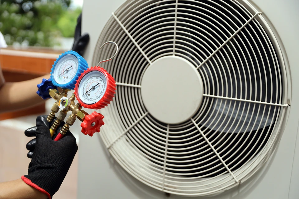 Extérieur résidentiel moderne avec unité de climatisation bi-split installée près d'une maison contemporaine aux façades sombre et claire, entourée de végétation et pelouse verte