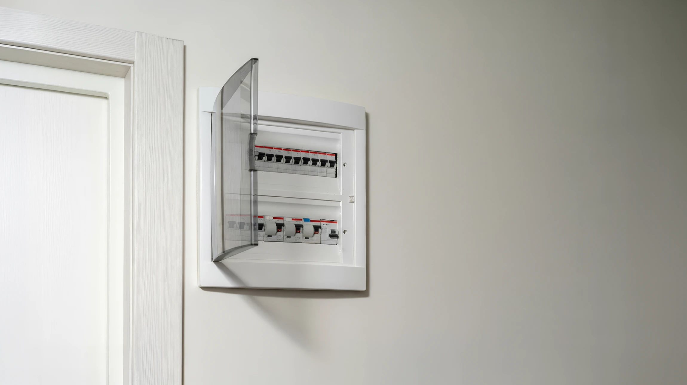 Électricien professionnel en salopette bleue et casque jaune dans cuisine moderne, portant câbles électriques et caisse à outils