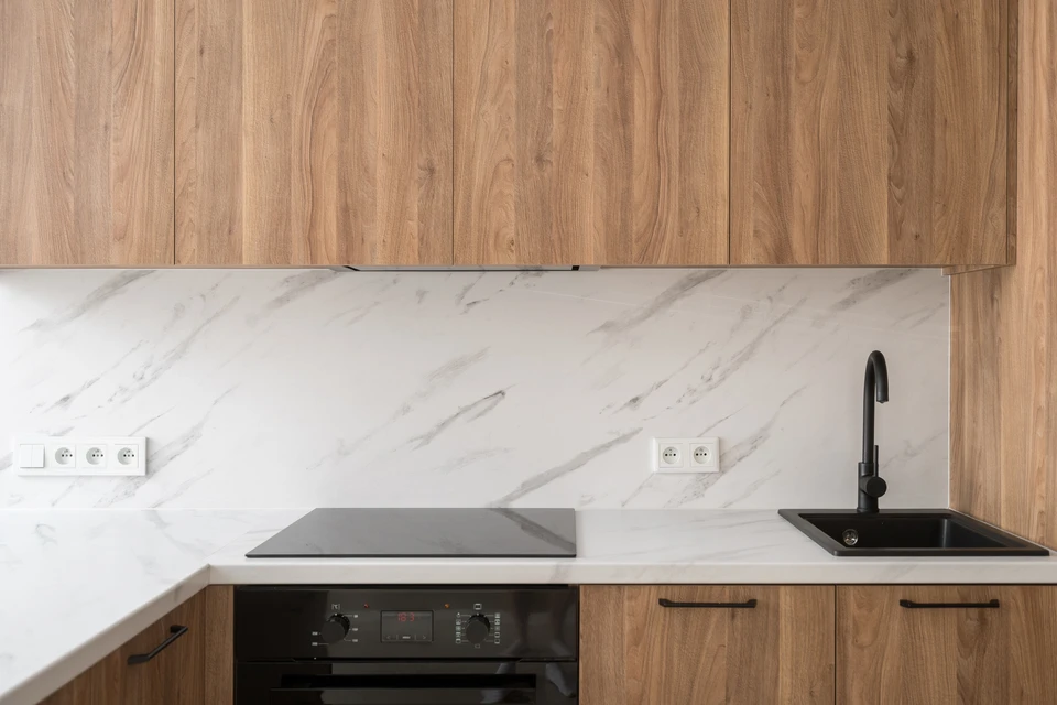 Technicien électricien travaillant sur tableau électrique industriel, portant gants de protection noirs avec liserés rouges